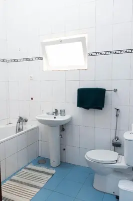 a white bathroom with a sink and a toilet at Palmarejo, Apartamento T1, frente Praça Center in Praia
