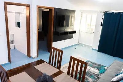 a living room with a table and a television at Palmarejo, Apartamento T1, frente Praça Center in Praia