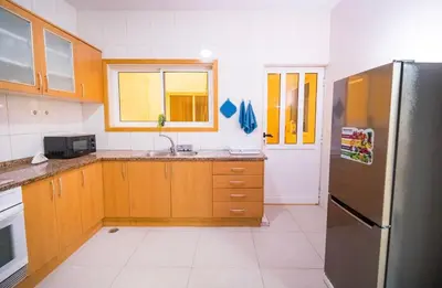 a kitchen with wooden cabinets and a stainless steel refrigerator at Cozy and beautiful apartment! in Praia
