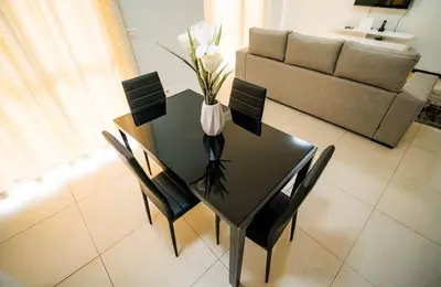a dining room table with chairs and a vase with flowers at Cozy and beautiful apartment! in Praia