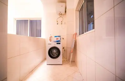 a washer and dryer in a white tiled bathroom at Cozy and beautiful apartment! in Praia