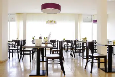 a dining room with tables and chairs and windows at Ouril Pontao Hotel in Santa Maria
