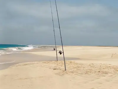 a pole sticking out of the sand on a beach at Salina's in Vila do Maio