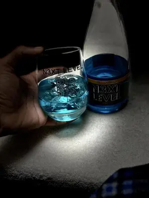 a person holding a glass of water next to a bottle at N3XT-LEVEL Pool in Praia