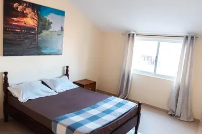 a bedroom with a bed and a large window at Apartamento T1 em Palmarejo, Trás de pão quente in Praia