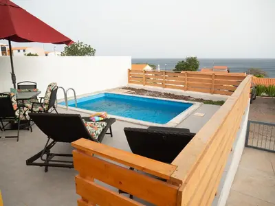 a swimming pool with two chairs and a table at Blue Coast Villas - Villa 6 in Cidade Velha