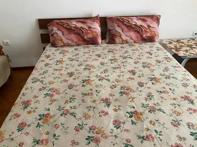 a bed with a floral comforter and two pillows at Apartamento em Monte in Mindelo