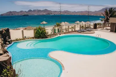 a swimming pool with the ocean in the background at Pôr D'Sôl Mindelo in Lazareto