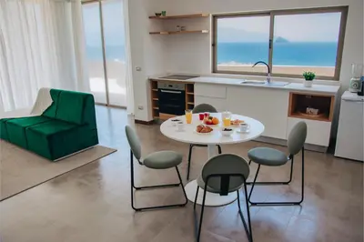 a kitchen with a table and chairs and a kitchen with the ocean at Pôr D'Sôl Mindelo in Lazareto