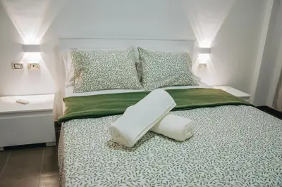 a bed with a green and white comforter and pillows at Pôr D'Sôl Mindelo in Lazareto