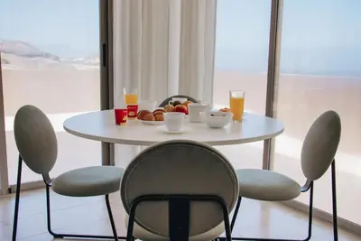 a white table with chairs and a bowl of fruit and drinks at Pôr D'Sôl Mindelo in Lazareto
