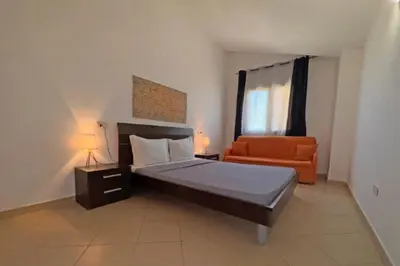 a bedroom with a bed and an orange chair at Morabeza Santa Maria - Djadsal Moradias in Santa Maria