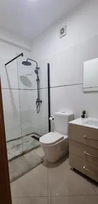 a bathroom with a shower and a toilet and a sink at Palmarejo Center Apartment Suites in Praia