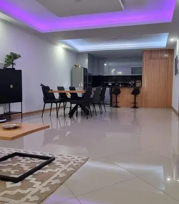 a dining room with a table and chairs and purple lights at Palmarejo Center Apartment Suites in Praia