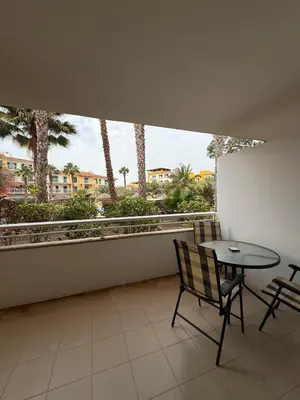 a balcony with a table and chairs and a large window at HostySpot - Vila Verde Resort in Santa Maria