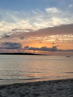 a sunset on the beach with a boat in the water at Casa Relaxa in Sal Rei