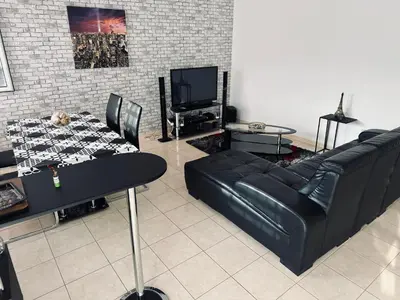 a living room with a black leather couch and a table at Condominio Finaçon praia ilha santiago in Prainha