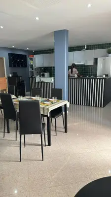 a dining room with a table and chairs and a person at Pensao Restaurante Recanto in Tarrafal