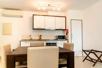 a kitchen with a wooden table and white cabinets at HostySpot - Melia Dunas in Santa Maria
