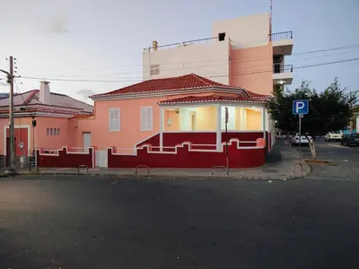 a pink building with a red fence next to a street at Vivenda Paraíso, Charming house on the Plateau in Praia