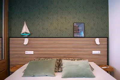 a bed with two pillows and a boat on the wall at Suncent apartment in Mindelo