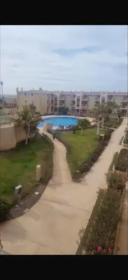 a walkway through a resort with a pool and buildings at Tropical Resort Pool View - Apartment in Santa Maria