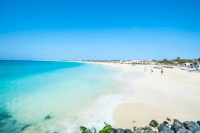 a beach with people walking on the sand and the water at Miguel House in Santa Maria
