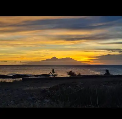 a sunset over the ocean with a mountain in the background at Casa Ida 1 Tarrafal, Santiago, Cabo Verde in Tarrafal