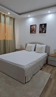 a bedroom with a large white bed with two pictures on the wall at T3 Duplex - Palmarejo Grande in Praia