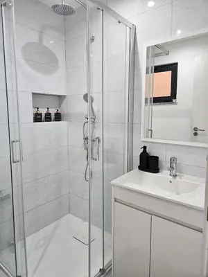 a white bathroom with a shower and a sink at T3 Duplex - Palmarejo Grande in Praia
