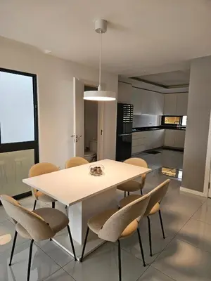 a white dining room table with chairs and a kitchen at T3 Duplex - Palmarejo Grande in Praia