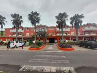 a large red building with palm trees in a parking lot at Casa Mendonça in Santa Maria