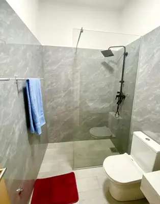 a bathroom with a shower with a toilet and a red rug at APARTAMENTO 403 T2 Centro de Sal Rei, Boavista in Sal Rei