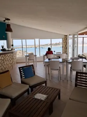 a restaurant with a person sitting at a table looking out at the ocean at Vivenda Mia in Beirona
