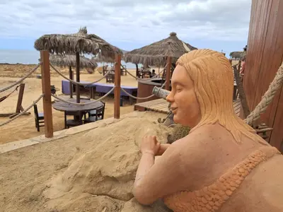 a statue of a woman sitting in the sand on the beach at Vivenda Mia in Beirona