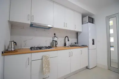 a kitchen with white cabinets and a sink and a refrigerator at Modern Gateway in Santa Maria