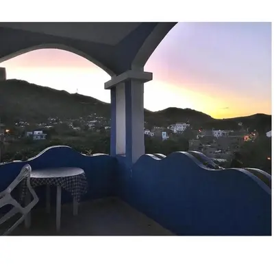 a table and a chair on a balcony with the sunset at Djabraba's Trail Triple SUITE in Vila Nova Sintra