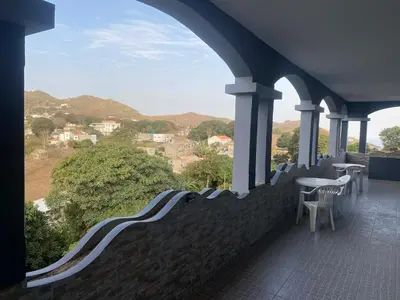 a balcony with chairs and a table and mountains at Djabraba's Trail Triple SUITE in Vila Nova Sintra