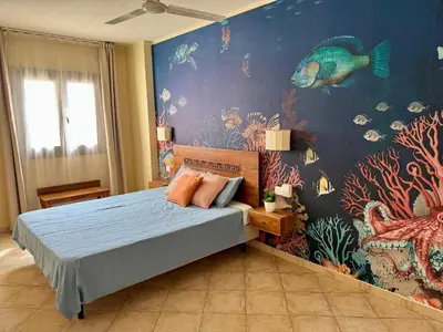 a bedroom with a bed with a fish mural on the wall at Tropical Mar Profundo in Santa Maria