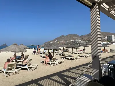 a group of people sitting on a beach with umbrellas at Cozy 1-Bedroom Getaway Steps from Laginha Beach in Mindelo