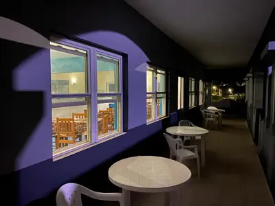 a purple room with tables and chairs and windows at Djabraba's Boarding Rooms in Garça