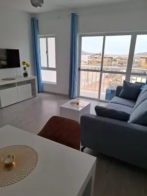a living room with a blue couch and a large window at Apartamentos Fatynybal in Espargos