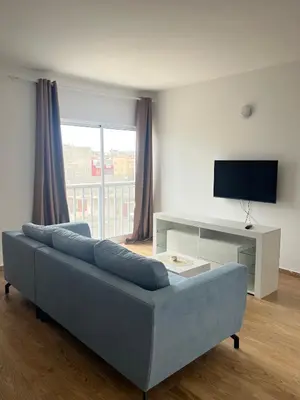 a living room with a blue couch and a television at Apartamentos Fatynybal in Espargos