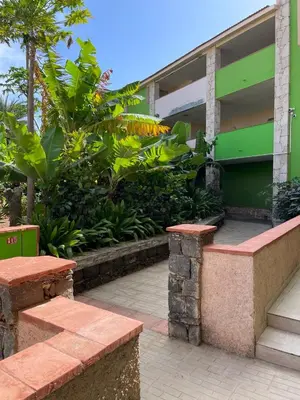 a green building with two benches in front of it at Djadsal Moradias - Near the ocean in Santa Maria