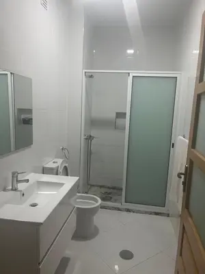 a white bathroom with a shower and a toilet at Aconchego da Bety in Praia