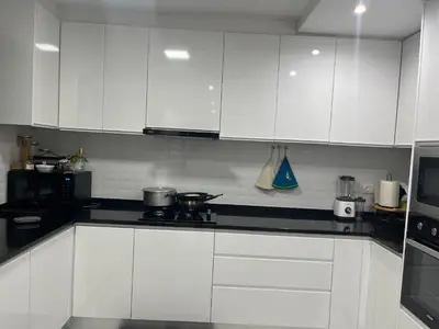 a white kitchen with black counter tops and white cabinets at Aconchego da Bety in Praia
