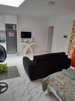 a living room with a black couch and a tv at Repousando no terraço in Ribeira Grande