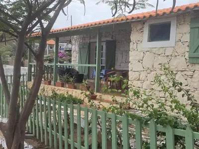a stone house with a green fence at Bougainvillea Villa in Cidade Velha