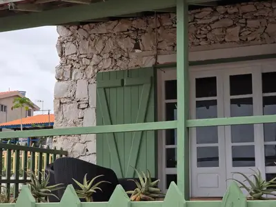 a green door on the side of a house with plants at Bougainvillea Villa in Cidade Velha