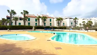 a swimming pool in front of a building with palm trees at Exclusive 3-Bedroom Apartment Vila Verde Resort in Santa Maria